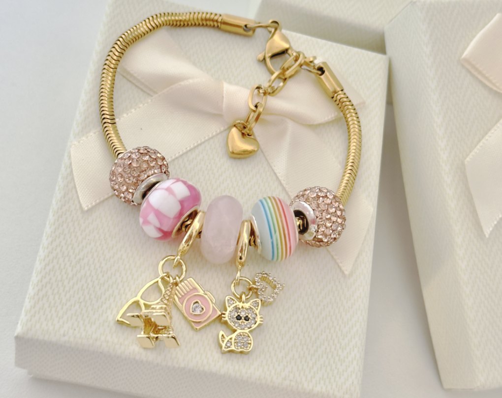 Pulsera dorada sobre cajas de regalo con lazo de satén
